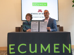 Dean Connie White Delaney and Ecumen President & CEO Cyrus Batheja holding up the signed documents commemorating the collaboratory between Ecumen and the U of M School of Nursing