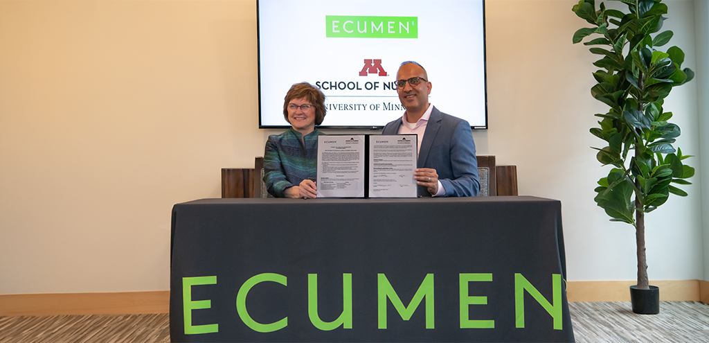 Dean Connie White Delaney and Ecumen President & CEO Cyrus Batheja holding up the signed documents commemorating the collaboratory between Ecumen and the U of M School of Nursing