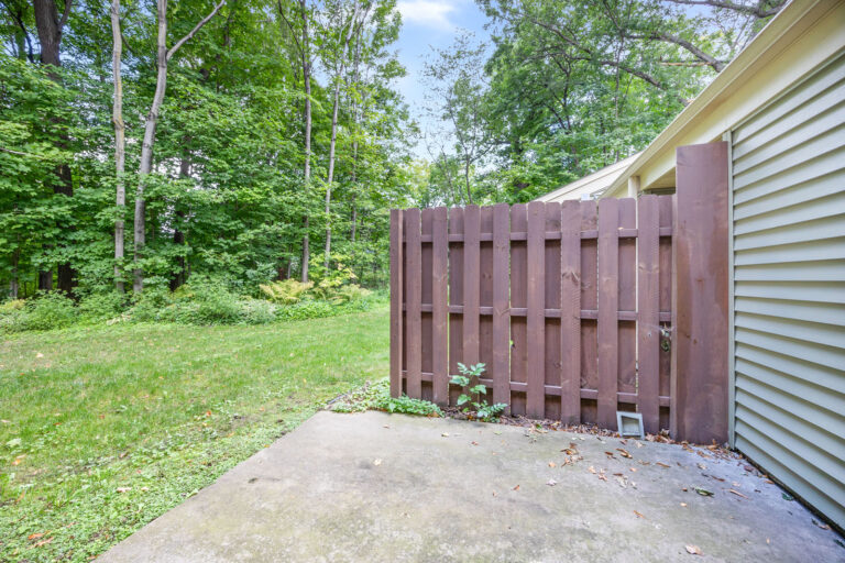 Exterior grass yard with concrete patio and wood privacy fence.