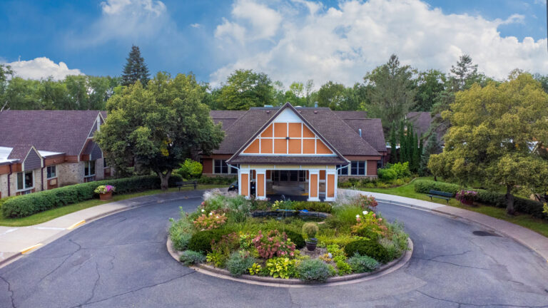 Aerial view of the main entrance driveway, lush garden, and carport, featuring terracotta and white Scandinavian design.