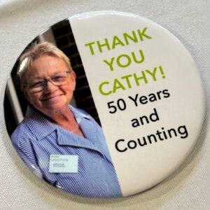 A round pin featuring a photo of a woman with text reading Thank You Cathy! 
